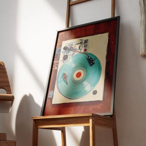 May include: A framed artwork featuring a vintage turntable design. The artwork has a teal record with a red center, set against a cream background. The frame is black, and the artwork is displayed on a wooden stand.