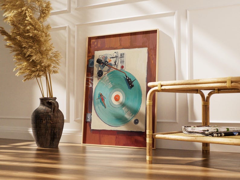 May include: A framed artwork featuring a vintage record player with a teal vinyl record. The artwork has a brown frame and is leaning against a white wall. A decorative vase with dried plants and a bamboo side table are also in the image.