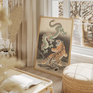 Puede incluir: Una impresión enmarcada que presenta un dragón verde y un tigre naranja en una escena de batalla dinámica. La obra de arte tiene una estética vintage, con un fondo neutro y un marco de madera. La impresión se exhibe en una habitación luminosa.