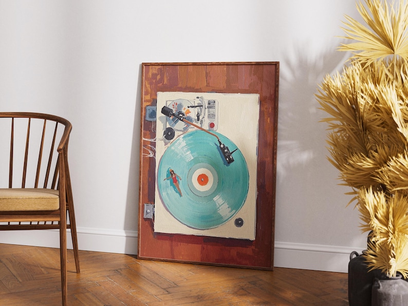 May include: A framed artwork depicts a vintage turntable with a teal record. The artwork has a brown wooden frame and is leaning against a white wall. A wooden chair with a yellow cushion is in the foreground.