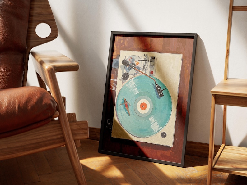 May include: Framed artwork featuring a vintage record player with a turquoise vinyl record. The artwork has a black frame and a brown border. The record has a red center and a painted design of a person surfing. The artwork is leaning against a white wall.