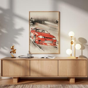 Puede incluir: Una impresión artística enmarcada representa un coche deportivo rojo corriendo en una pista, en un estilo acuarela. La obra de arte se exhibe sobre un mueble de madera, con una lámpara moderna y objetos decorativos.