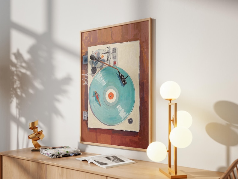 May include: A framed artwork depicts a vintage record player with a teal record. The artwork is mounted on a white wall above a wooden cabinet. A modern lamp with four spherical lights and a gold sculpture are on the cabinet.