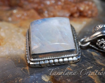 May include: A silver pendant with a square, white moonstone set in a silver bezel. The pendant is on a silver chain with a decorative clasp.
