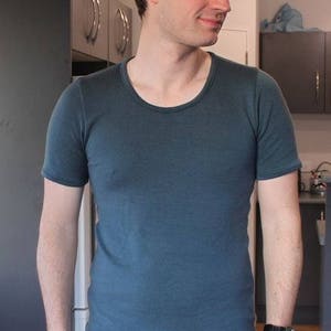 May include: A man wearing a dark blue t-shirt and black jeans.