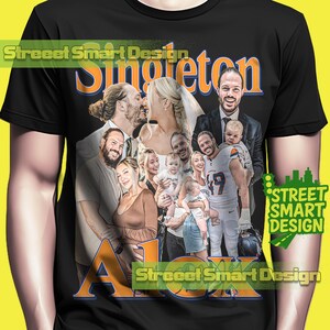 May include: Black t-shirt featuring a family portrait with the name "Singleton" in orange and blue. The design includes multiple images of a family, with the name "Alex" in orange at the bottom. The shirt has the text "Street Smart Design".