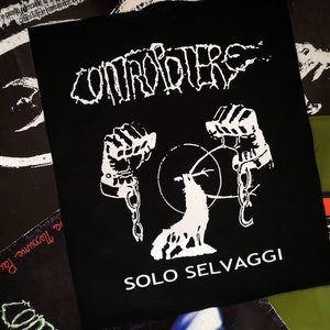 May include: Black and white patch with the text "CONTROLLERS SOLO SELVAGGI" and a graphic of two chained hands holding a wolf with a chain around its neck.