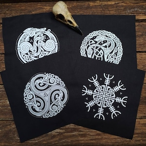 May include: Four black fabric patches with white embroidered designs. The designs include a knotwork pattern, a bird within a circle, a knotwork pattern with three intertwined snakes, and a knotwork pattern with eight spokes.
