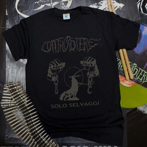 May include: Black t-shirt with a band logo, "CONTROPIERE", in a stylized font. The logo is above a graphic of a wolf with chains around its paws. The text "SOLO SELVAGGI" is below the graphic.