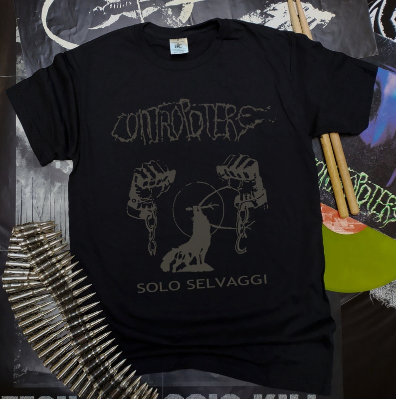 May include: Black t-shirt with a band logo, "CONTROPIERE", in a stylized font. The logo is above a graphic of a wolf with chains around its paws. The text "SOLO SELVAGGI" is below the graphic.