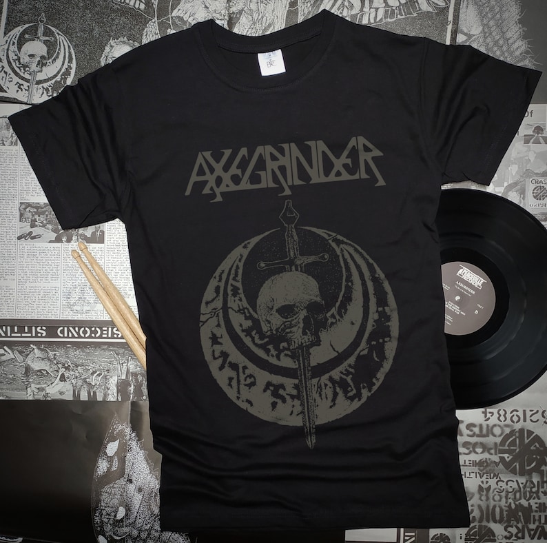 May include: Black t-shirt with a gray skull and sword graphic. The text "AXGRINDER" is printed above the graphic.