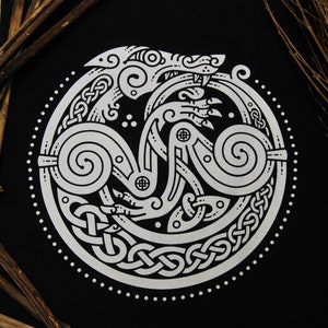 May include: A black t-shirt featuring a white design of a wolf within a Celtic knot pattern.