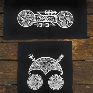 Può includere: Due toppe rettangolari in tessuto nero con disegni serigrafati bianchi. La toppa superiore presenta una disposizione orizzontale di due spirali triskelion collegate da intrecci complessi. La toppa inferiore mostra un motivo semicircolare con disegni geometrici sopra due disegni circolari a intreccio.