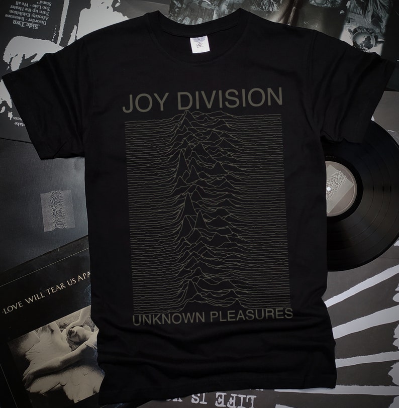 May include: Black t-shirt with a graphic print of the Joy Division album cover "Unknown Pleasures". The graphic is a black and white image of a series of lines that form a mountain range.