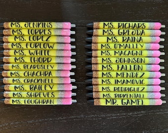 Può includere: Un set di 24 penne glitter gialle e rosa con scrittura nera. Ogni penna ha un nome diverso scritto su di essa, tra cui "MS. JENKINS", "MS. TORRES", "MS. LOPEZ", "MS. FURLOW", "MS. WHITE", "MS. THORP", "MS. BEARDSLEY", "MS. CHACHRA", "MS. CRACKNELL", "MS. BAILEY", "MS. SHREVES", "MS. LOUGHRAN", "MS. RICHARS", "MS. GREODA", "MS. RAINA", "MS. O'MALLEY", "MS. MACAGNE", "MS. JOHNSON", "MS. FALLON", "MS. MENDEZ", "MS. IMAMOVIC", "MS. RODRIGUEZ", "MS. BIRKENTALL" e "MR. GAMEL".