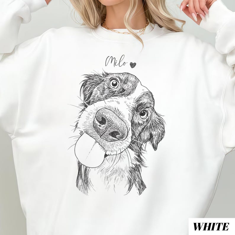 May include: White sweatshirt featuring a black and white dog illustration with its tongue out. The name "Milo" is written above the dog's head, with a heart symbol. The word "WHITE" is printed in the bottom right corner.