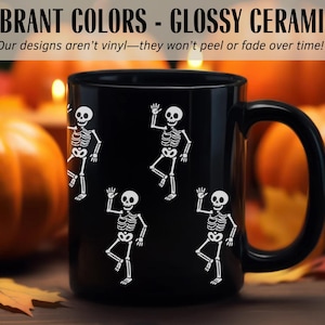 May include: Black ceramic mug with white skeleton illustrations. The mug has a large handle and features the text "VIBRANT COLORS - GLOSSY CERAMIC!" and "Our designs aren't vinyl-they won't peel or fade over time!" in white.