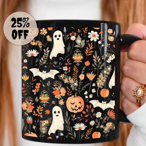May include: Black ceramic mug with a Halloween-themed floral design. The design includes white ghosts, bats, pumpkins, and various flowers in orange, white, and yellow. The mug has a black handle and the text "25% OFF" in a circular sticker.