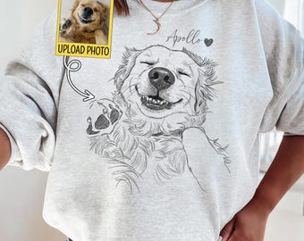 May include: Ash gray sweatshirt featuring a smiling dog sketch with the name "Apollo" and a heart. An "UPLOAD PHOTO" graphic is above the dog sketch. The sweatshirt is worn by a person.