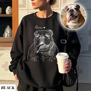 May include: Black sweatshirt featuring a white line drawing of a bulldog with the name "Rocco" above it. A small image of a bulldog is in the upper right corner. The word "BLACK" is at the bottom of the image.