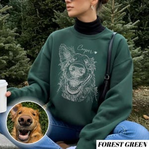 May include: Forest green sweatshirt with a white line drawing of a dog's face and the name "Cooper" above it. A small inset photo shows the dog's face. The sweatshirt is a solid color and has a crew neck.