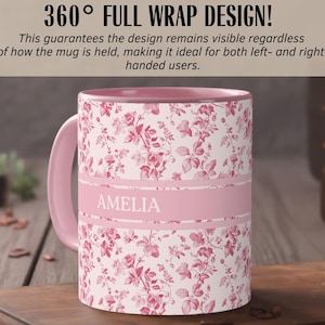 May include: A pink floral mug with the name "AMELIA" in white letters. The mug has a pink handle and interior. The design features a repeating pattern of red flowers on a white background. The text "360&deg; FULL WRAP DESIGN!" is at the top.