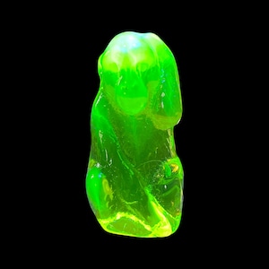 May include: A bright green glass figurine of a sitting monkey. The figurine is made of uranium glass and glows under a black light.