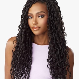 May include: A woman with long, black, curly faux locs. The hair cascades down the shoulders and chest. She is wearing a light purple tank top. The background is a solid, neutral color.