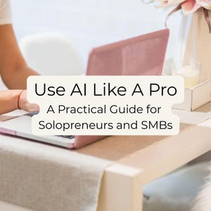 May include: A laptop with a pink cover is open on a table. The text "Use AI Like A Pro" and "A Practical Guide for Solopreneurs and SMBs" is displayed on a white background. A person's arm and hand are visible, interacting with the laptop.