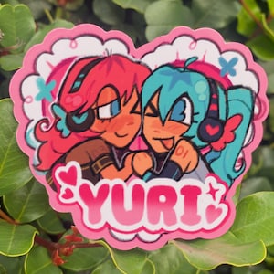 May include: A heart-shaped sticker featuring two anime-style characters embracing. One character has red hair, the other has blue hair. The sticker has a pink border with the word "YURI" in pink letters.