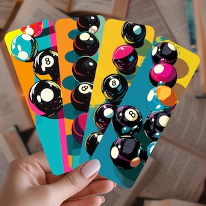 May include: Four colorful bookmarks featuring stylized illustrations of billiard balls. Each bookmark has a different background color, including teal, orange, and yellow. The number 8 ball is prominently displayed on several of the balls.