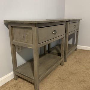 May include: Two gray wooden nightstands with a single drawer and a lower shelf. Each nightstand has a simple, modern design.