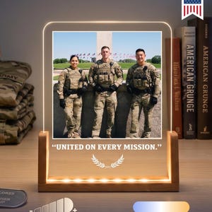 May include: A rectangular acrylic photo display with a wooden base featuring an illuminated image of three soldiers in uniform. The text "UNITED ON EVERY MISSION." is printed below the photo, accompanied by a laurel wreath graphic icon.
