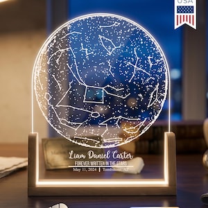May include: A personalized night light featuring a circular design with a constellation map. The light is set in a wooden frame and displays the text "Liam Daniel Carter FOREVER WRITTEN IN THE STARS May 11, 2024 Tombstone, AZ". It has dimmable and cool-warm white light settings.