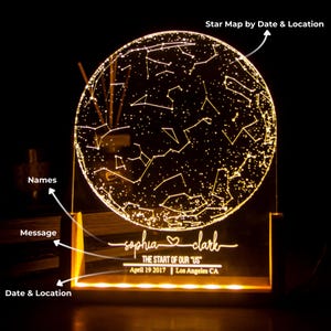 Puede incluir: Una luz nocturna de mapa de estrellas personalizada con una base de acr&iacute;lico transparente y una esfera redonda iluminada. La esfera muestra las constelaciones visibles el 19 de abril de 2017 en Los &Aacute;ngeles, California. La base est&aacute; grabada con los nombres "sophia" y "clark" y el texto "THE START OF OUR "US"".