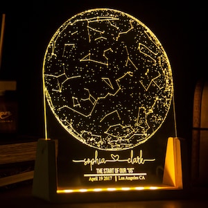 Puede incluir: Una luz nocturna personalizada con un mapa de constelaciones, los nombres "sophia" y "clark", el texto "THE START OF OUR "US"", la fecha "April 19 2017" y la ubicaci&oacute;n "Los Angeles CA".