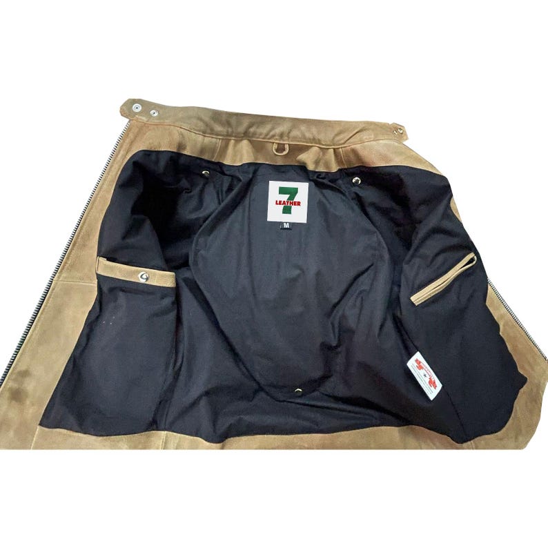May include: The inside of a brown leather jacket with a black lining. The jacket has a zipper closure and two pockets. The label on the inside of the jacket says "7 Leather" and "M".