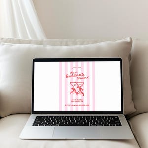 May include: Laptop displaying a pink and white striped invitation for "Olivia's Bachelorette Weekend." The invitation features two red cocktail glasses with bows, event details, and a phone number. The laptop is on a white pillow.