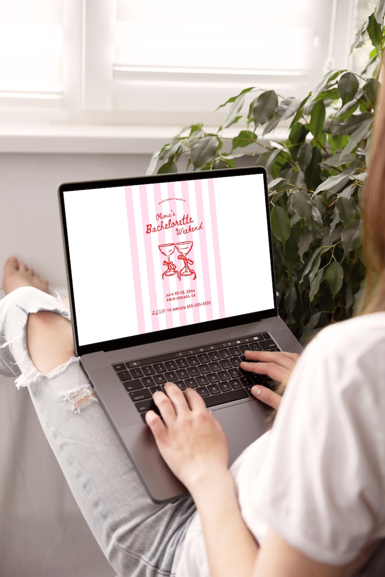 May include: A laptop displaying a pink and white invitation for "Olivia's Bachelorette Weekend." The invitation features two champagne glasses with bows, event details, and a phone number. The laptop is on a person's lap.