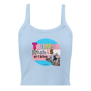 May include: Light blue tank top with spaghetti straps. The front features a circular design with the text "Trans Rights or I bites" in colorful letters, set against the trans pride flag colors and a dog image.