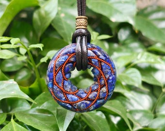 May include: A circular pendant made of blue lapis lazuli stone chips wrapped in copper wire. The pendant hangs from a dark brown cord secured by a small, cylindrical, patterned brass bead at the top of the stone ring.