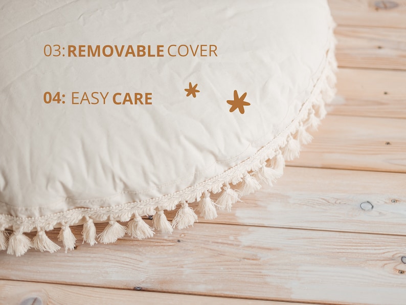 May include: A cream-colored round cushion with a white tassel trim. The cushion has the text "03: REMOVABLE COVER" and "04: EASY CARE" printed on it. Two brown stars are also printed on the cushion.