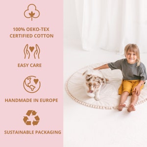 May include: A white play mat with a brown pom-pom border. A child is sitting on the mat with a puppy. The mat is made of 100% Oeko-Tex certified cotton, is easy care, handmade in Europe, and comes in sustainable packaging.
