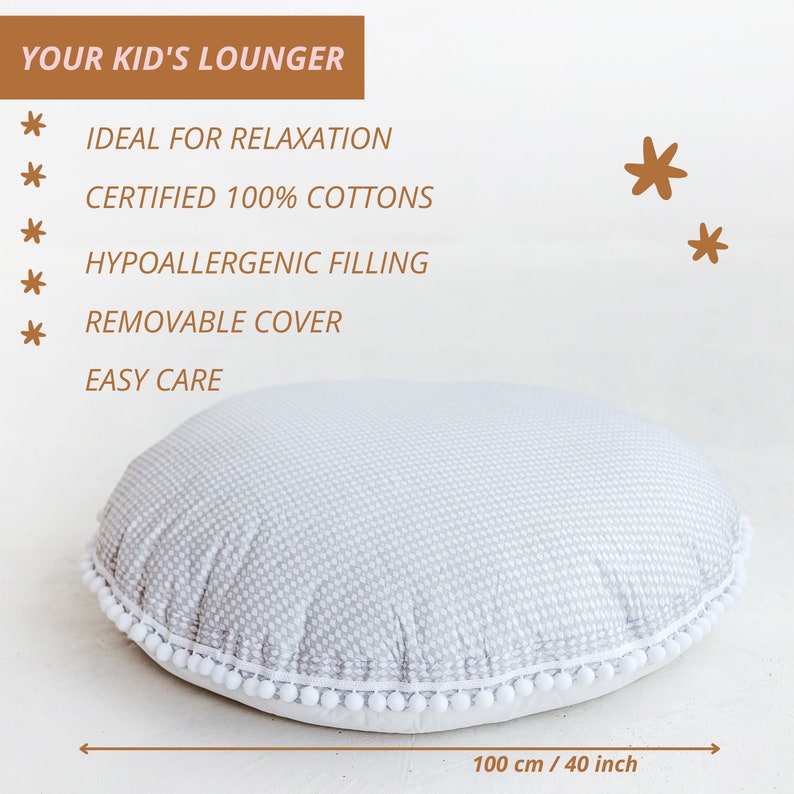 May include: A gray and white round lounger with a white pom-pom trim. The lounger is 40 inches in diameter. The text "YOUR KID'S LOUNGER" is at the top of the image. The text "IDEAL FOR RELAXATION", "CERTIFIED 100% COTTONS", "HYPOALLERGENIC FILLING", "REMOVABLE COVER", and "EASY CARE" are listed below the title.