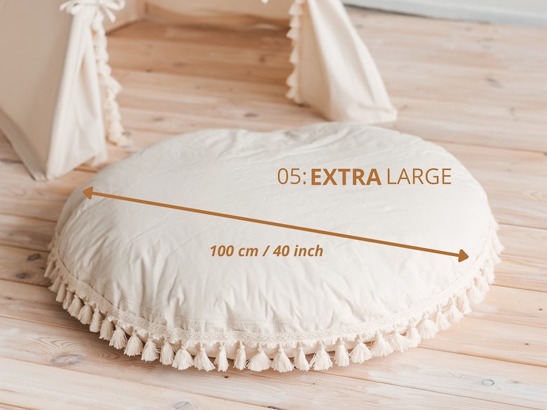 May include: A large, round, cream-colored cushion with a white fringe border. The cushion measures 40 inches in diameter. The text "05: EXTRA LARGE" and "100 cm / 40 inch" is printed on the cushion.