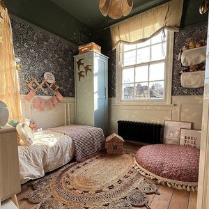Pu&ograve; includere: Una camera da letto per bambini con un letto singolo, un tappeto e un cuscino rotondo. Le pareti sono rivestite con carta da parati floreale e la stanza ha un'atmosfera fantasiosa. Il testo sul muro dice "Born to be Wild".