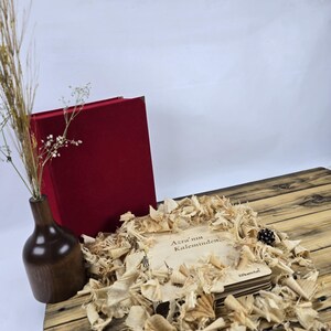 May include: A stack of wooden coasters with the text "Azra'un Kaleminden" in brown lettering on a light brown background. The coasters are surrounded by wood shavings and a red velvet box.