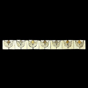 May include: A decorative border featuring seven rectangular tiles. Each tile has a white background and a stylized tulip design with silver and gold accents. The border is set against a black background.