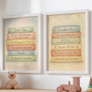 Puede incluir: Dos impresiones enmarcadas con pilas de libros infantiles clásicos. Una impresión muestra títulos como "Peter Pan" y "Alicia en el país de las maravillas". La otra presenta "Cenicienta" y "Caperucita Roja". Las impresiones están en marcos blancos y se exhiben en una estantería de madera.