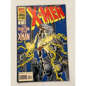 May include: X-Men comic book cover featuring Storm in a silver outfit with yellow lightning effects. The title reads "X-Men" in yellow and red, with the text "The Seduction of an X-Man". The comic is a Direct Edition, Annual #3, 1994.